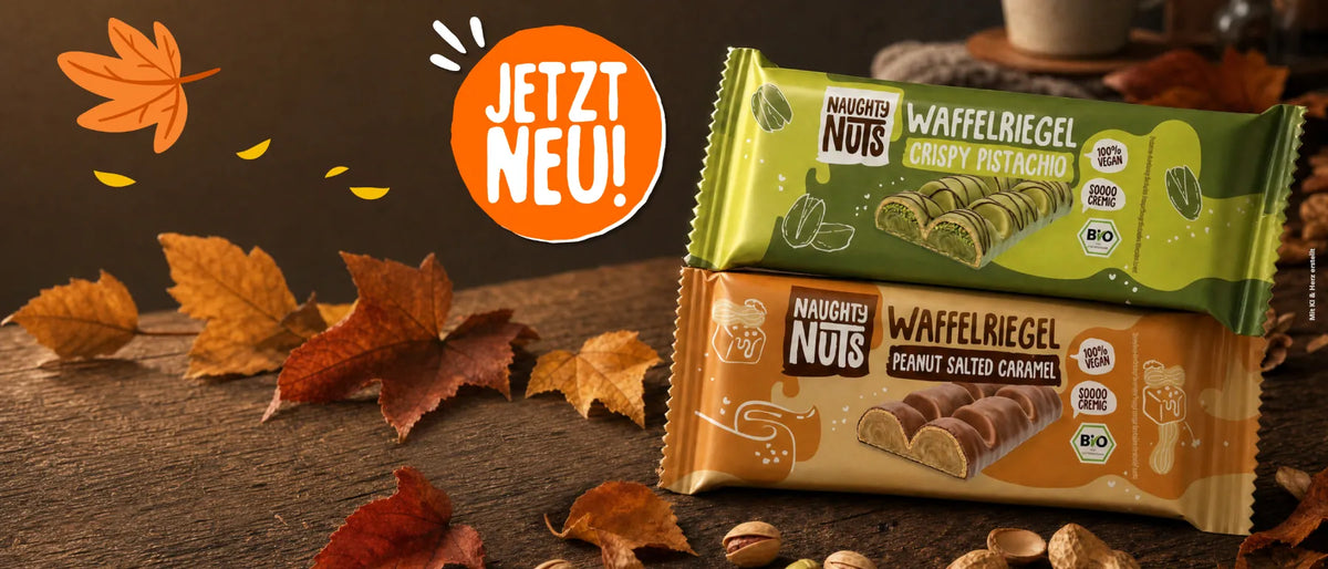Naughty Nuts Waffelriegel in den Sorten Crispy Pistachio und Peanut Salted Caramel auf herbstlichem Holzhintergrund